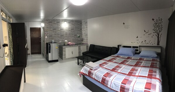 A modern bedroom with a large bed, a sofa, and a kitchenette in the background. - Muangthongthani Rental by Khun Dan (Pak Kret)