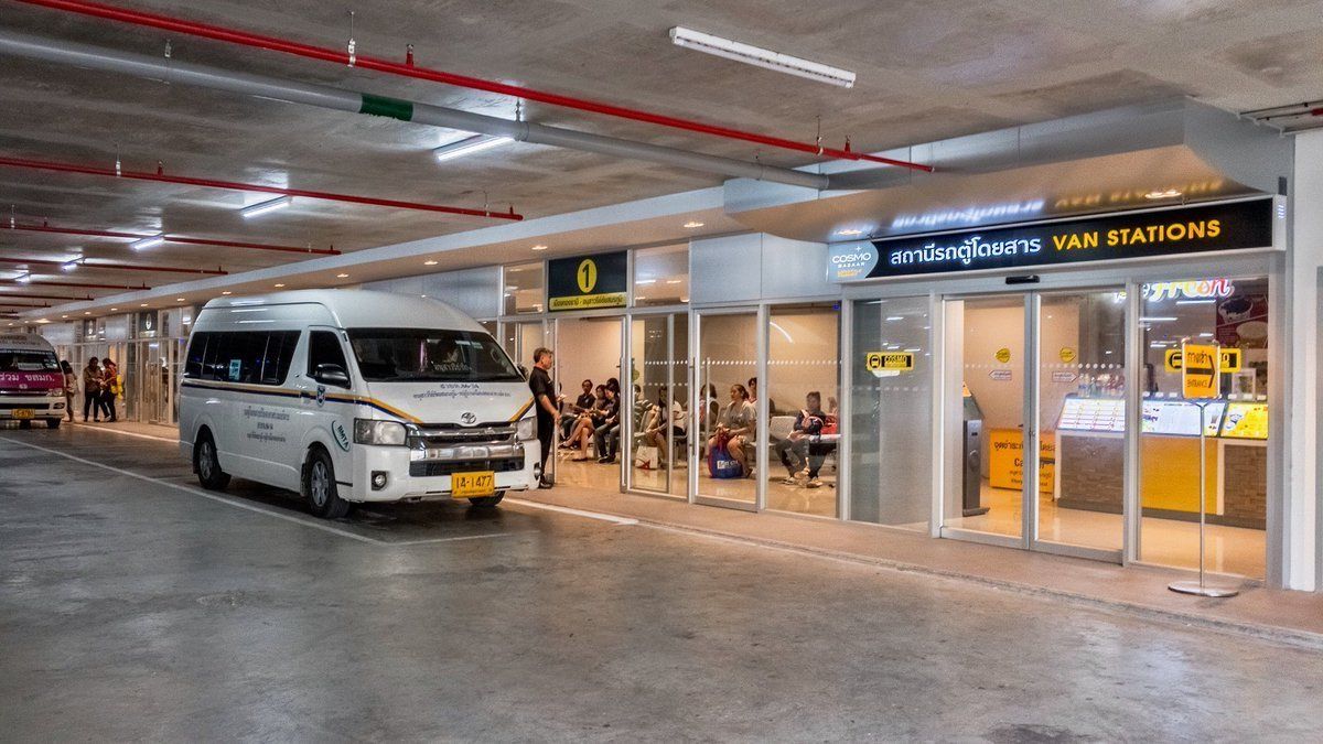 A van parked in a covered area with people sitting inside a building.