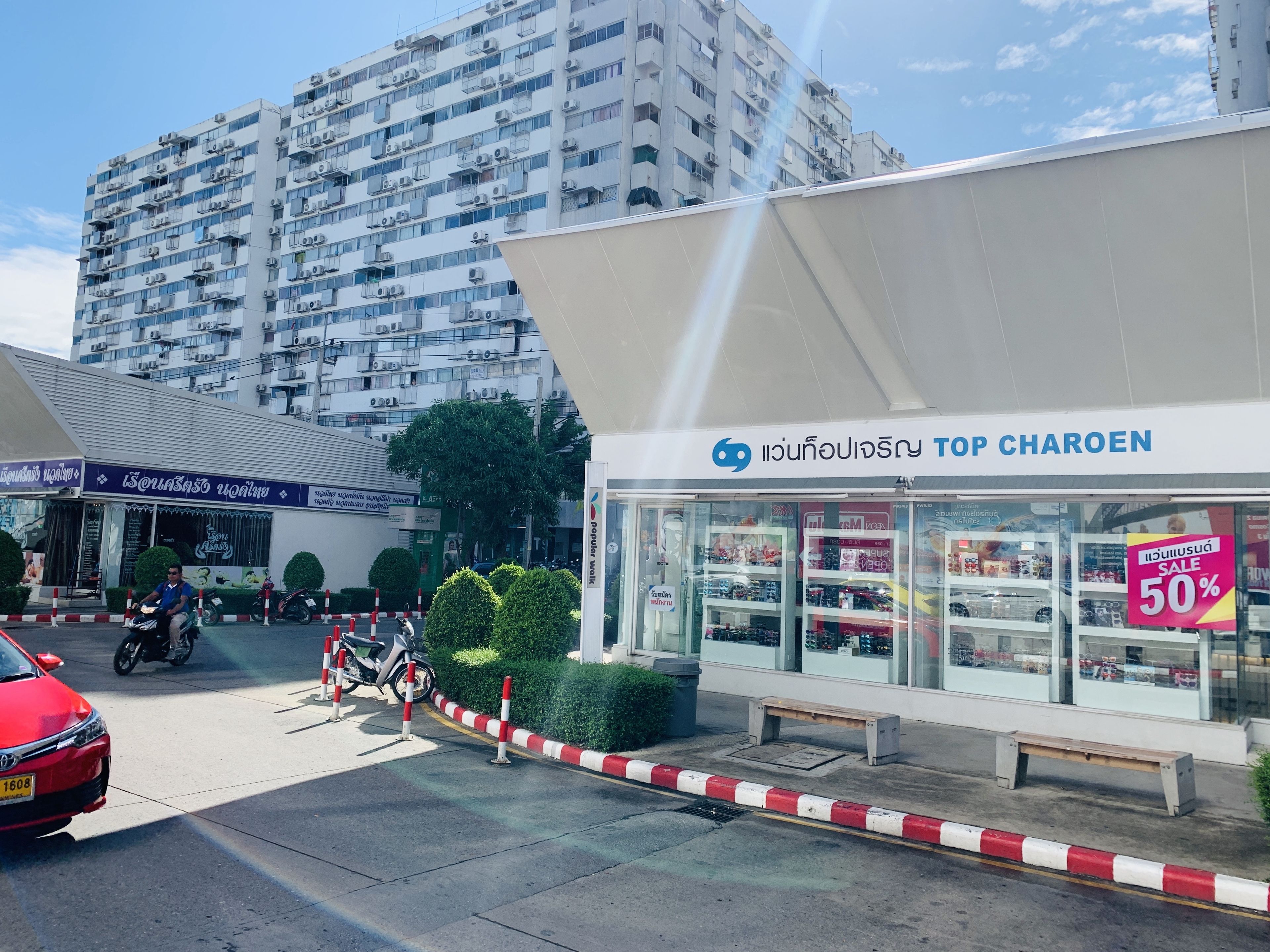 Vista de la calle con un edificio identificado como 'Top Charoen' y un cartel de ofertas.