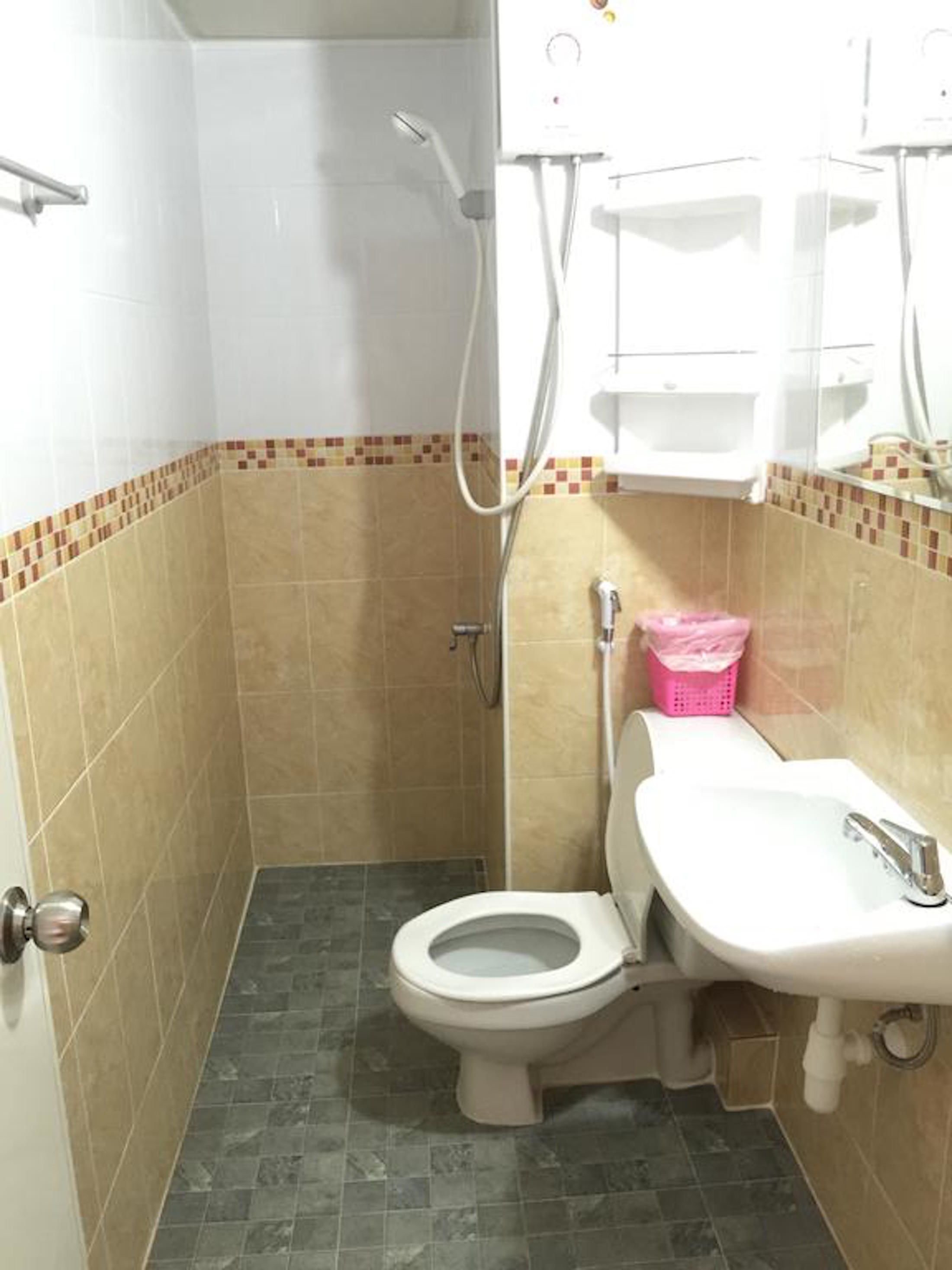 A small bathroom with a toilet, sink, and shower.