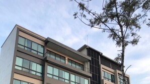 A multi-story hotel with large windows, a covered outdoor seating area, and a modern architectural design. - The Residence Thepkanjana (Krathum Baen)