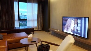 A modern living room with a sofa, armchair, and a TV on a wall.
