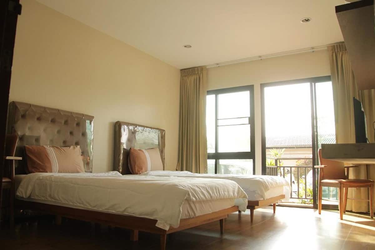 A hotel room with two beds, a balcony, and a piano.