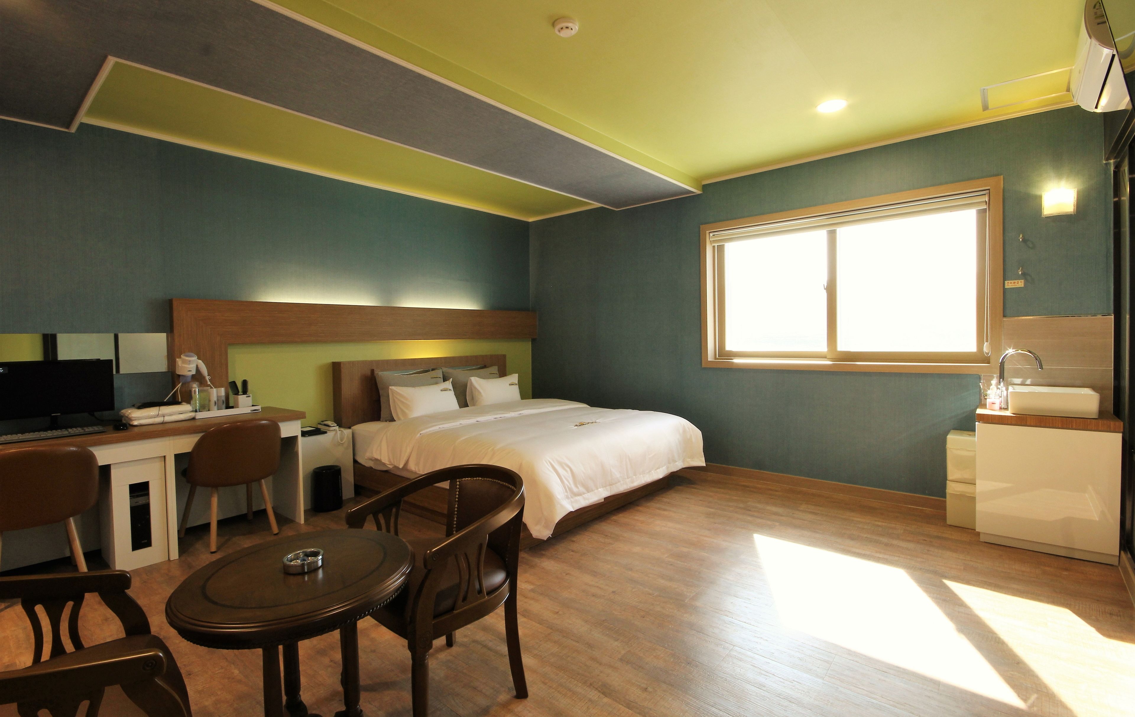 A hotel room with a bed, desk, chairs, and a window.