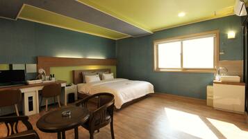 A hotel room with a bed, desk, chairs, and a window.