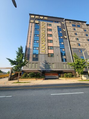 A modern hotel building with a prominent 'Golden Root' sign, multiple floors, and a gated entrance. - GoldenRoot Hotel in Gimhae (Gimhae)