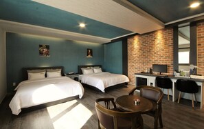 Habitación de hotel con dos camas, un escritorio con computadora y un área de comedor con sillas.