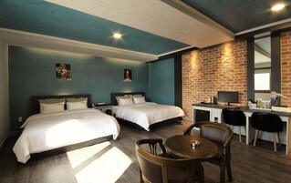 Habitación de hotel con dos camas, un escritorio con computadora y un área de comedor con sillas.
