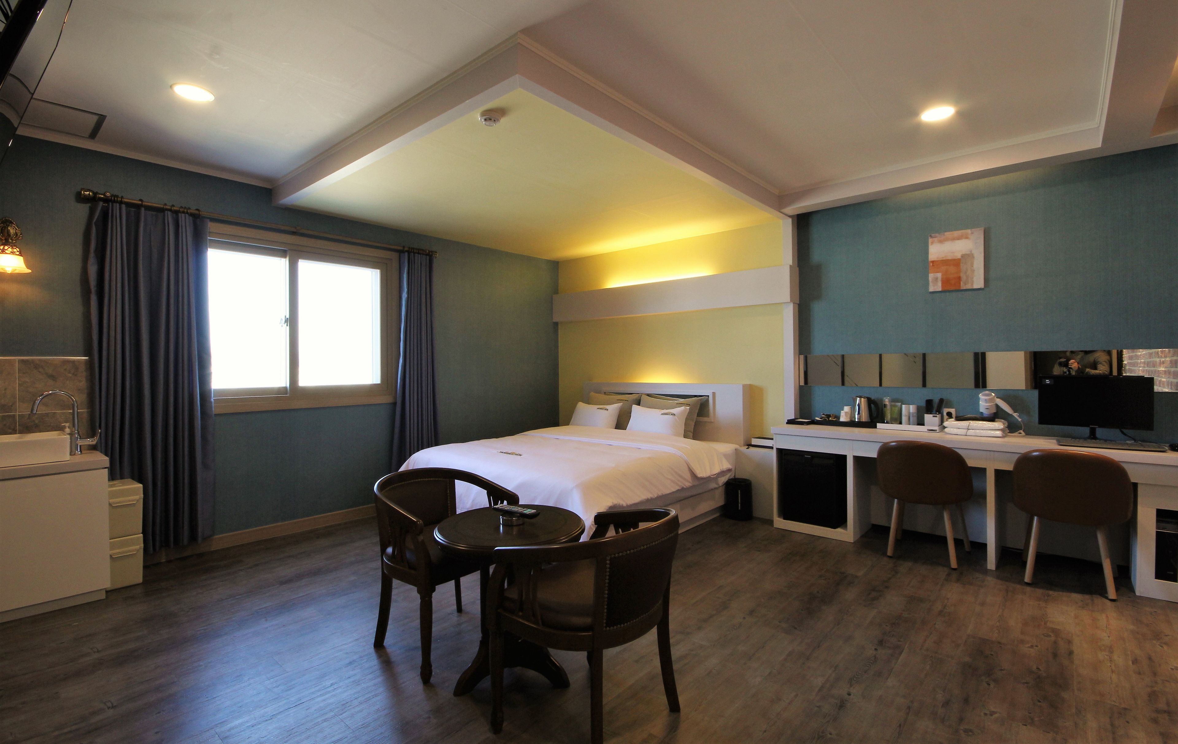 A hotel room with a bed, desk, chairs, a small table, and a window.
