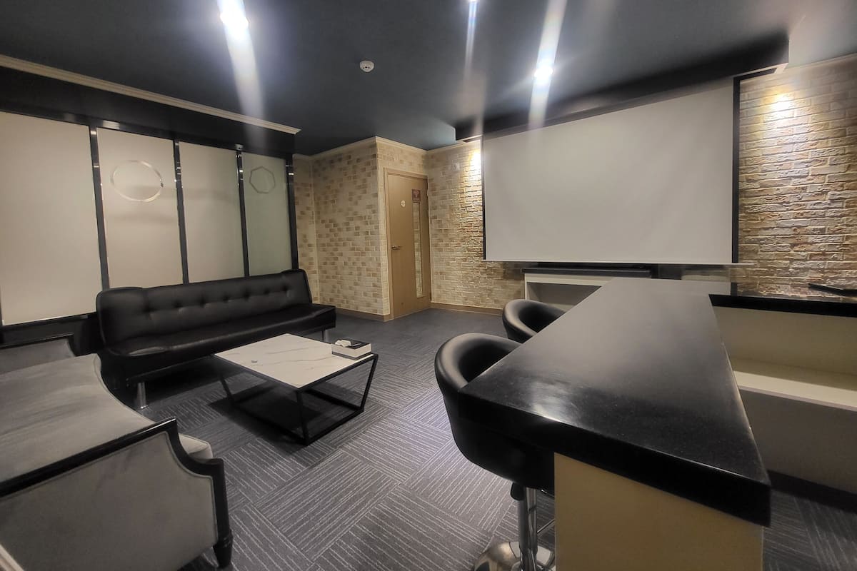 A modern conference room with a black leather sofa, a glass-top table, and a whiteboard.