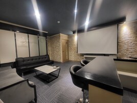 Una sala de conferencias moderna con un sofá de cuero negro, una mesa con cubierta de vidrio y una pizarra.