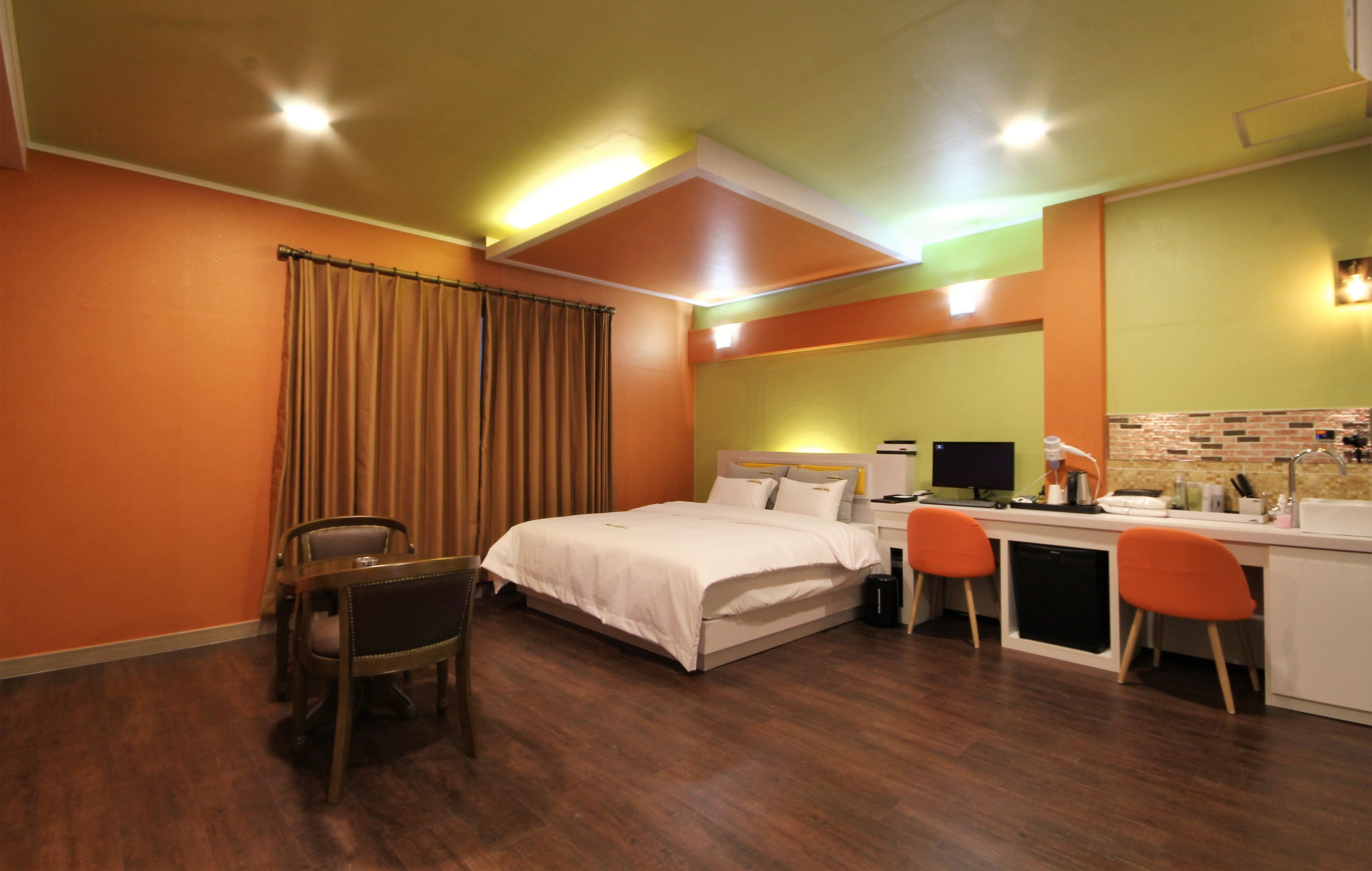 Habitación de hotel con cama, escritorio, sillas y kitchenette.
