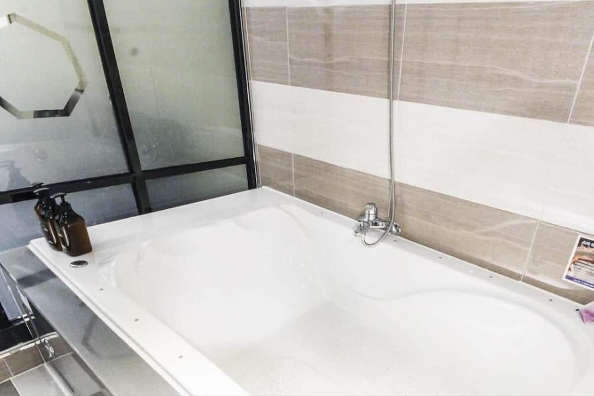 A bathroom with a large bathtub, a glass shower enclosure, and a tiled wall.