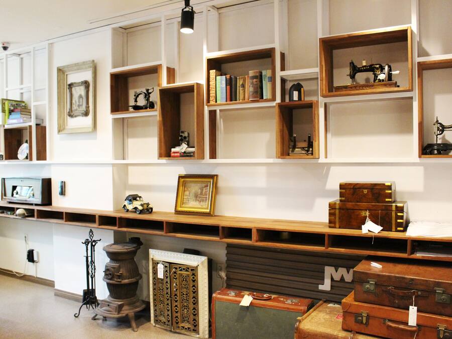 A room with shelves displaying various items including books, sewing machines, and suitcases.