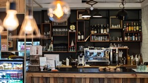 A bar with wooden shelves stocked with bottles and glasses, a coffee machine, and a refrigerator with drinks. - GONGGAN Residence Hotel (Geoje)