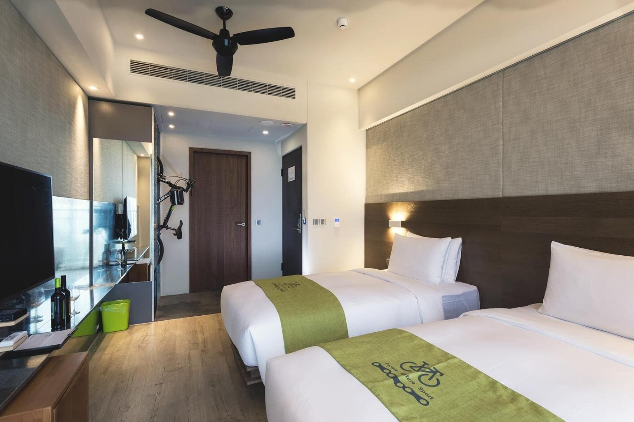 A hotel room with two beds, a TV, a desk, and a mirror.