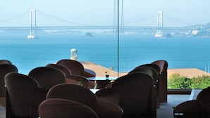 Uitzicht vanuit een restaurant, met een tafel en stoelen gericht op een grote hangbrug over het water.