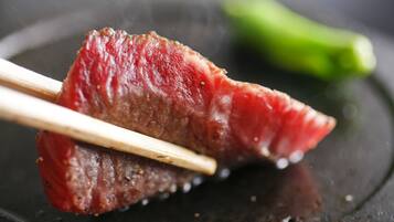 A piece of meat on a plate with chopsticks.