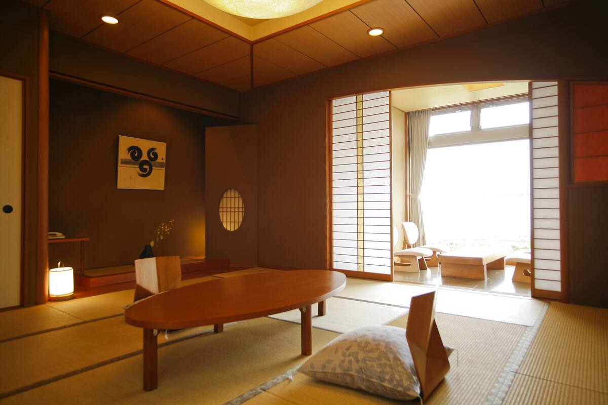 Ein traditioneller japanischer Raum mit Tatami-Bodenbelag, einem niedrigen Holztisch und Schiebetüren.
