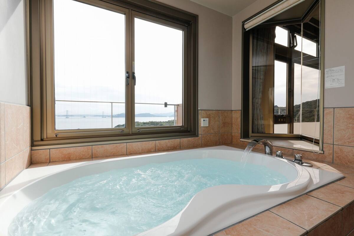 Ein Badezimmer mit einer Badewanne, einem Fenster und Blick auf eine Brücke.