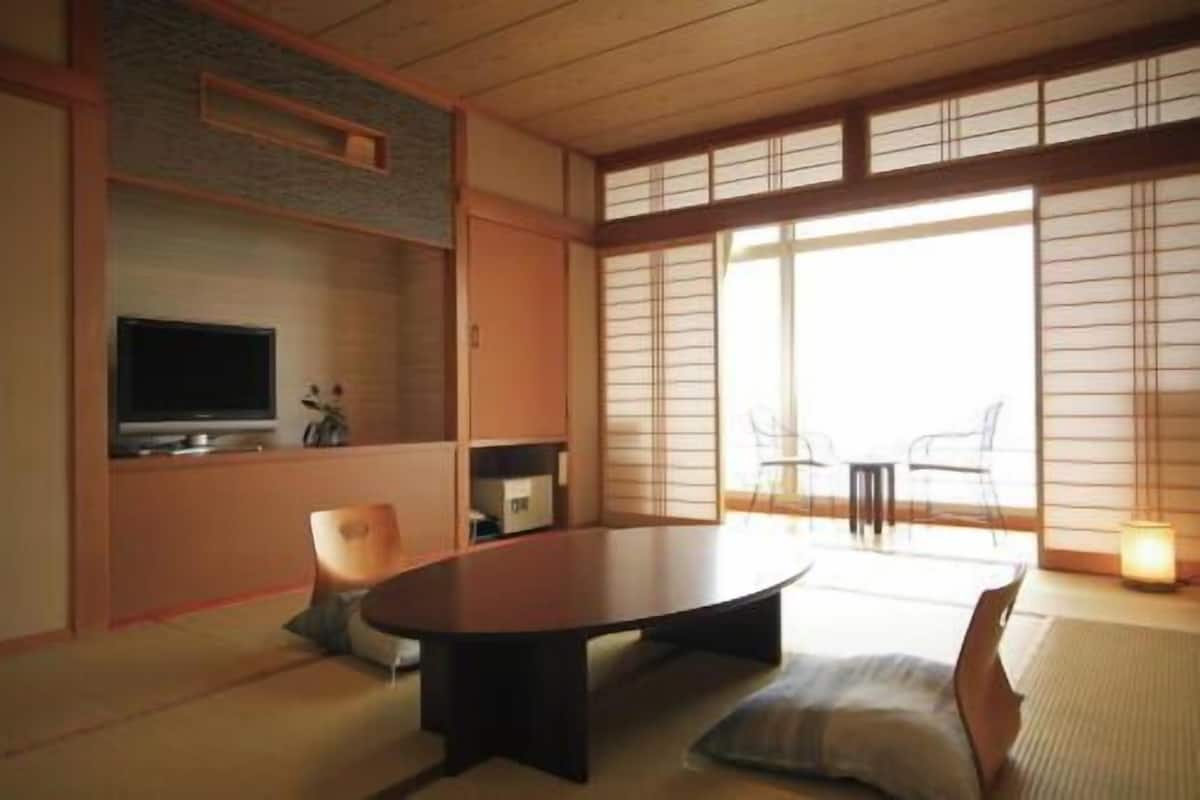 Una habitación tradicional japonesa con suelo de tatami, una mesa baja y puertas correderas.