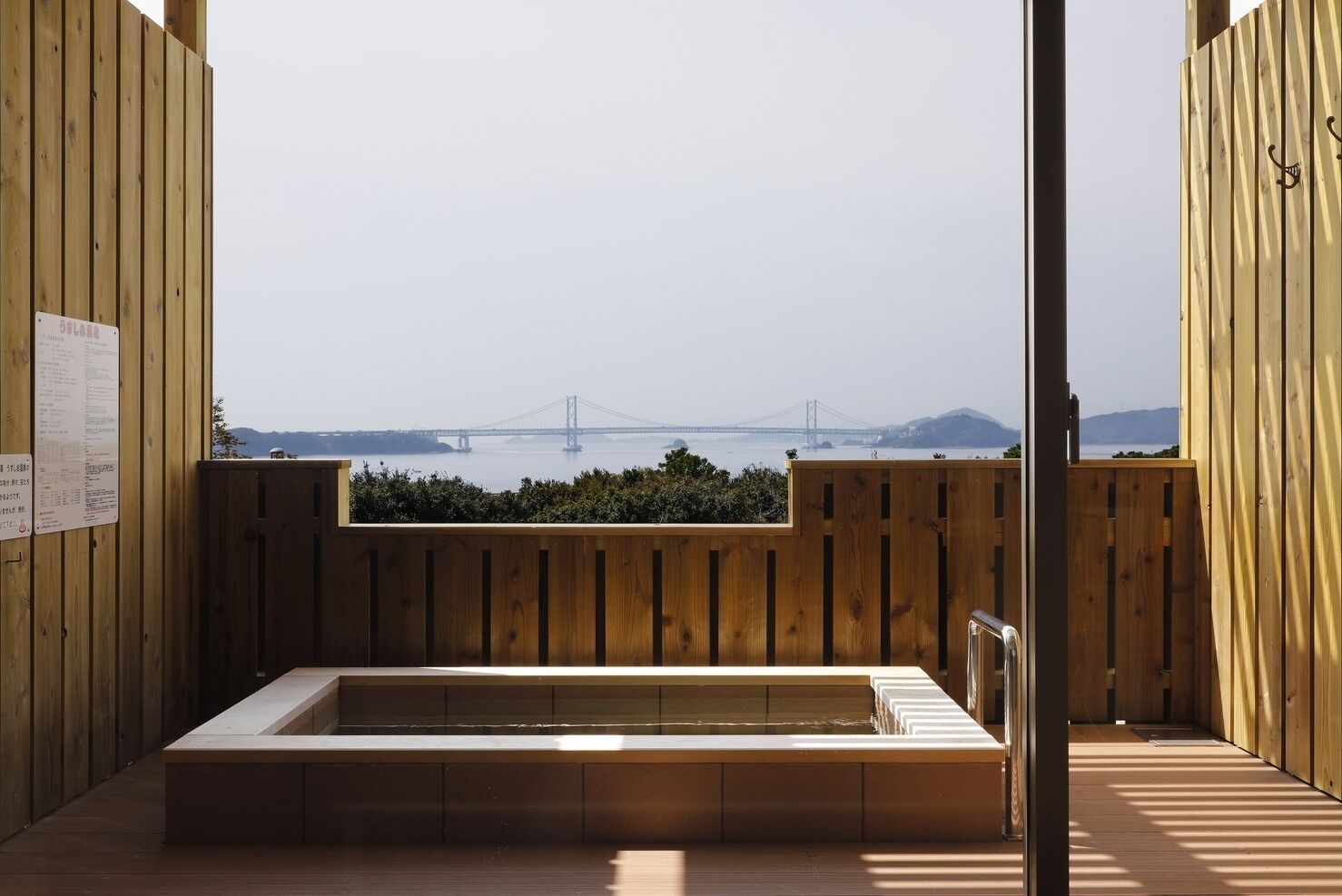 A wooden room with a view of a bridge and mountains.