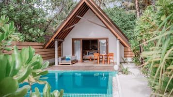 A modern villa with a pool, wooden deck, and a dining area.