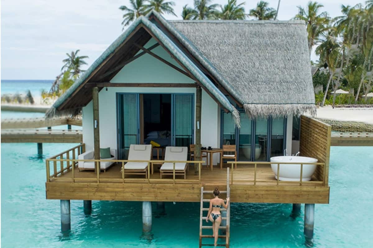 An overwater bungalow with a thatched roof, wooden deck, and a private pool.