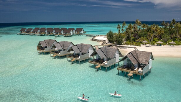Overwater bungalows with clear turquoise water, a sandy beach, and palm trees. - Fushifaru Maldives (Fushifaru)