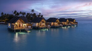 Overwater bungalows with private pools, connected by walkways, set against a twilight sky. - Fushifaru Maldives (Fushifaru)