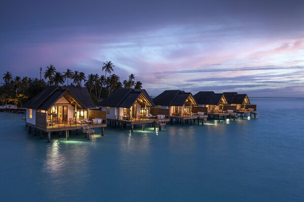 Overwater bungalows with private pools, connected by walkways, set against a twilight sky. - Fushifaru Maldives (Fushifaru)