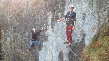 Dos personas descendiendo por un acantilado rocoso.
