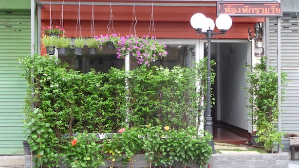 Un bâtiment avec un toit rouge, une porte en verre et un petit jardin agrémenté de diverses plantes et fleurs.