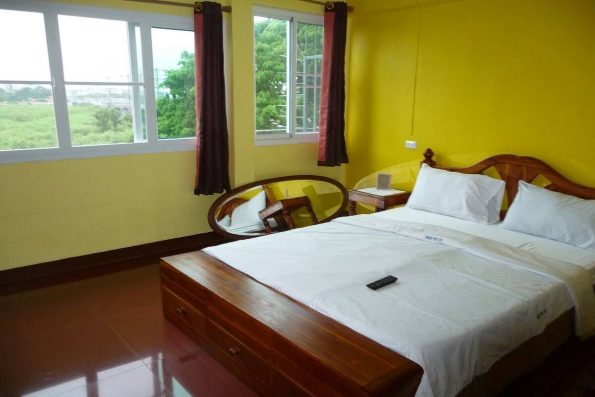 A bedroom with a bed, a bedside table, a chair, and a window with curtains.