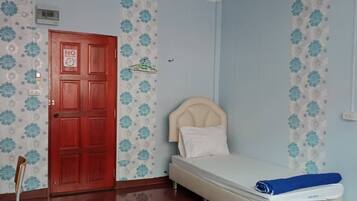 A room with a bed, a door, and a wall with floral wallpaper.