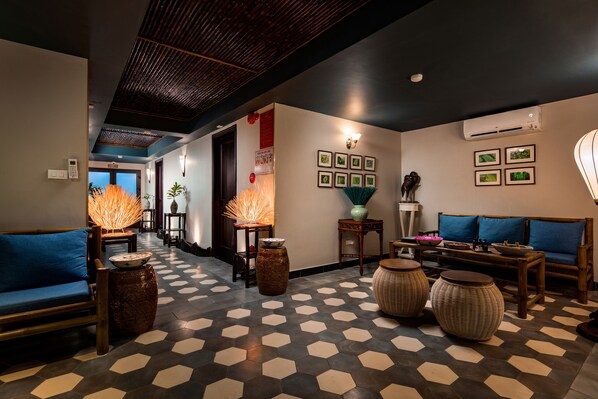 A hotel lobby with a geometric patterned floor, wooden furniture, and wall-mounted picture frames.