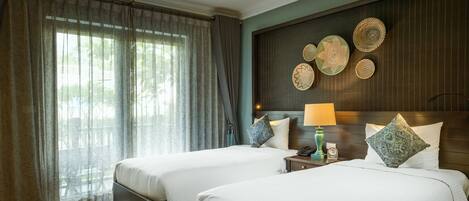 A hotel room with two beds, a ceiling fan, a wall with decorative plates, and a window with curtains.