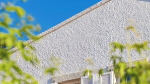 A stone building with a thatched roof, white shutters, and a window with a view. - Alacati Roka Tas Otel (Cesme)