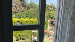 A view through a window of a backyard with a swimming pool, a lawn, and a garden. - Alacati Roka Tas Otel (Cesme)