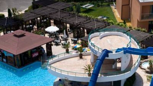 En vandpark med flere vandrutsjebaner og pools, omgivet af liggearealer og en bygning med et cirkulært design.