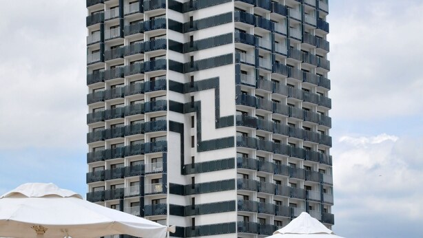 Un hotel de gran altura con un patrón en zigzag distintivo, múltiples balcones y una terraza en la azotea.