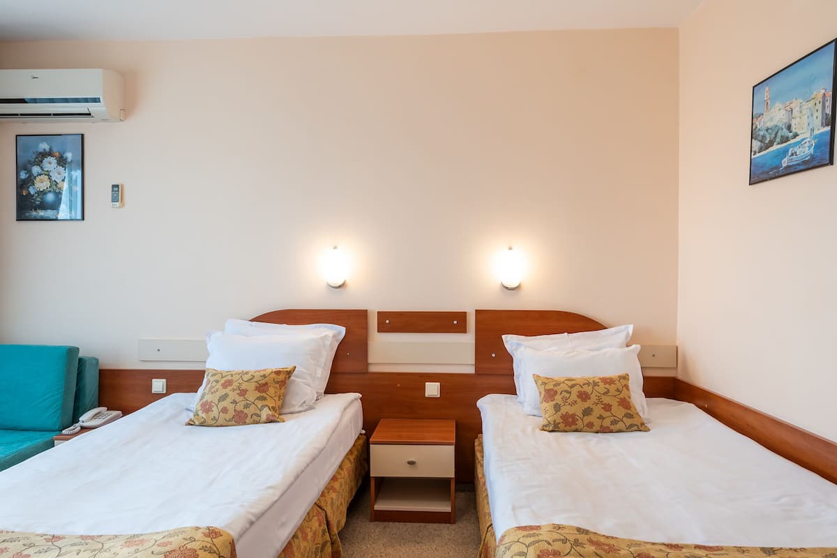 Habitación de hotel con dos camas, una mesita de noche, un teléfono y un cuadro en la pared.