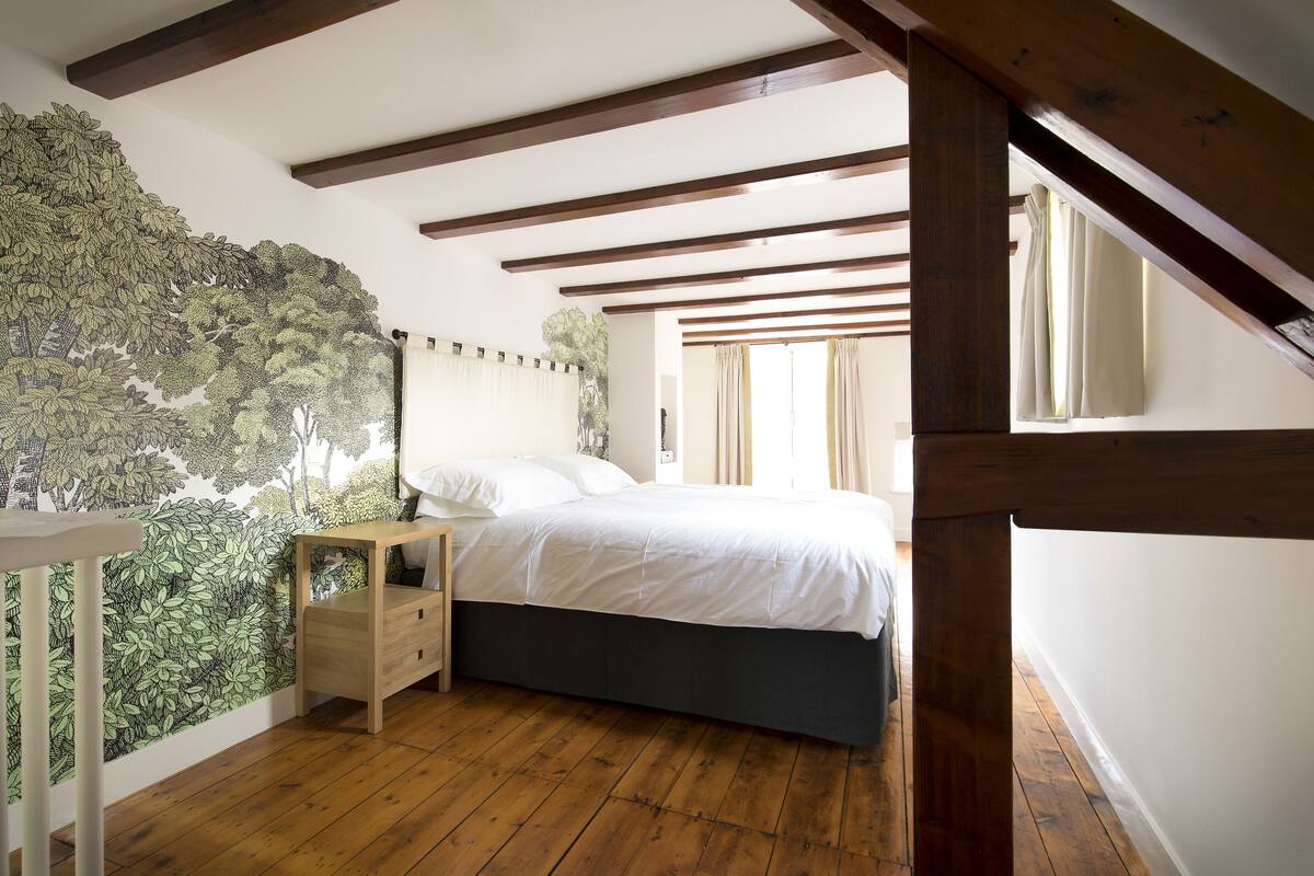 Un dormitorio con cama, suelo de madera y un mural en la pared.