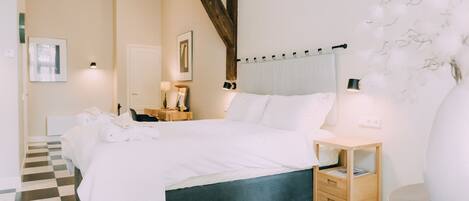 A bedroom with a checkered floor, a bed with white bedding, a wooden nightstand, and a bedside table with a lamp.
