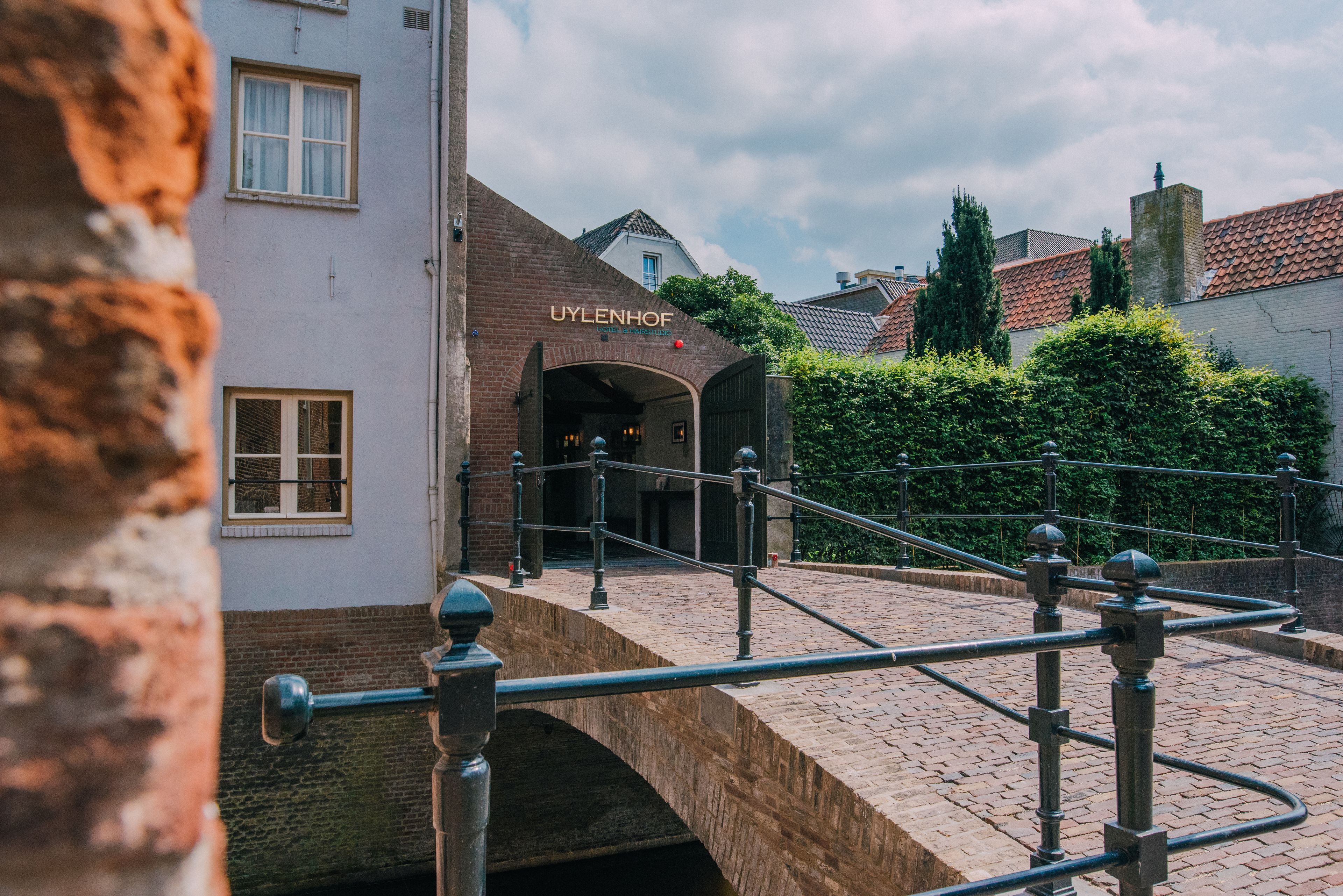 A brick building with a sign reading "UYLENHOF" and a stone bridge leading to it.