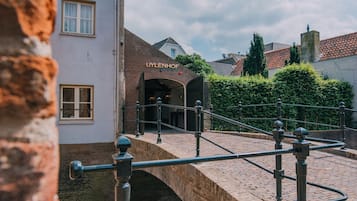 A brick building with a sign reading "UYLENHOF" and a stone bridge leading to it.