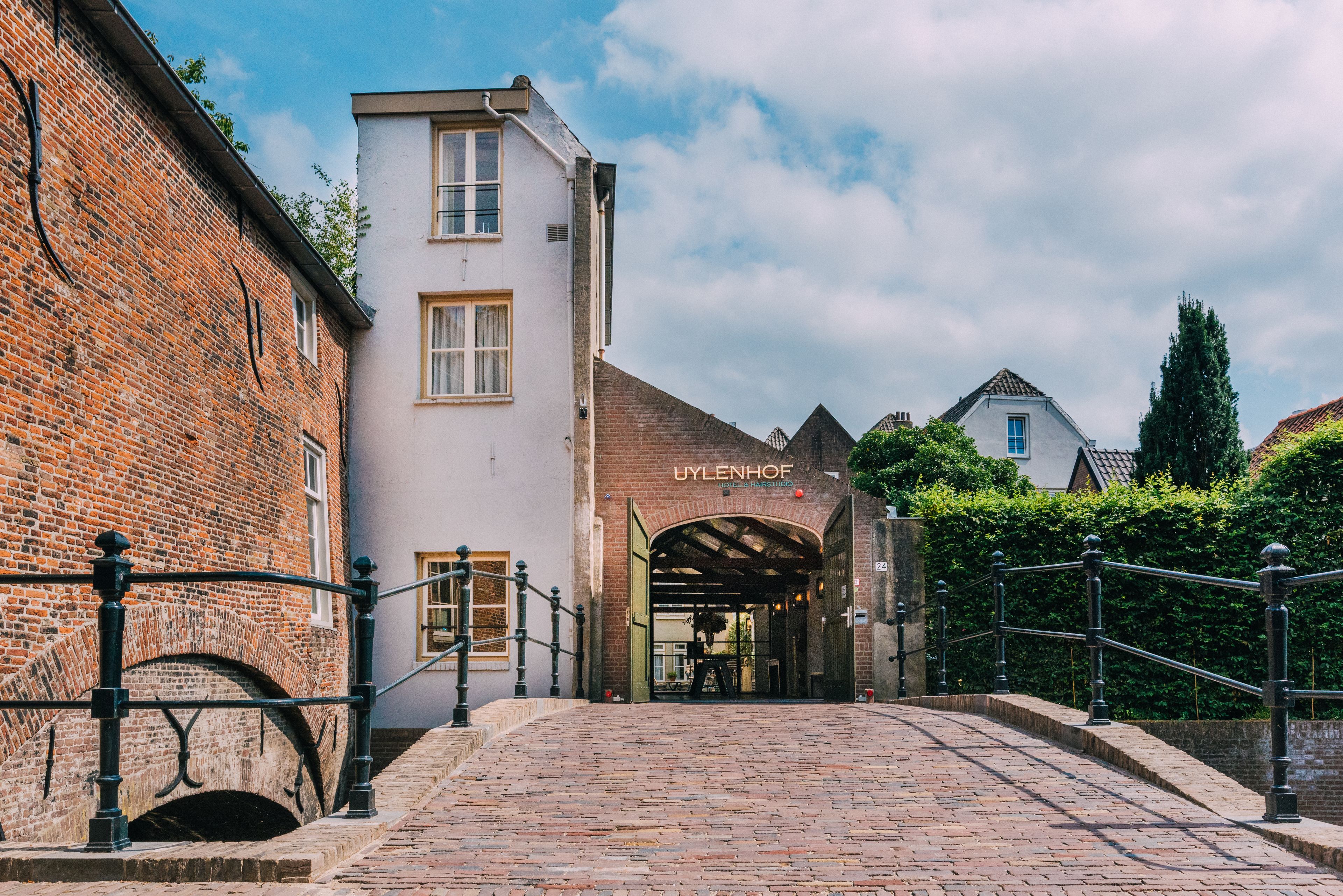 A cobblestone pathway leading to a building with a sign reading "UYLENHOF".