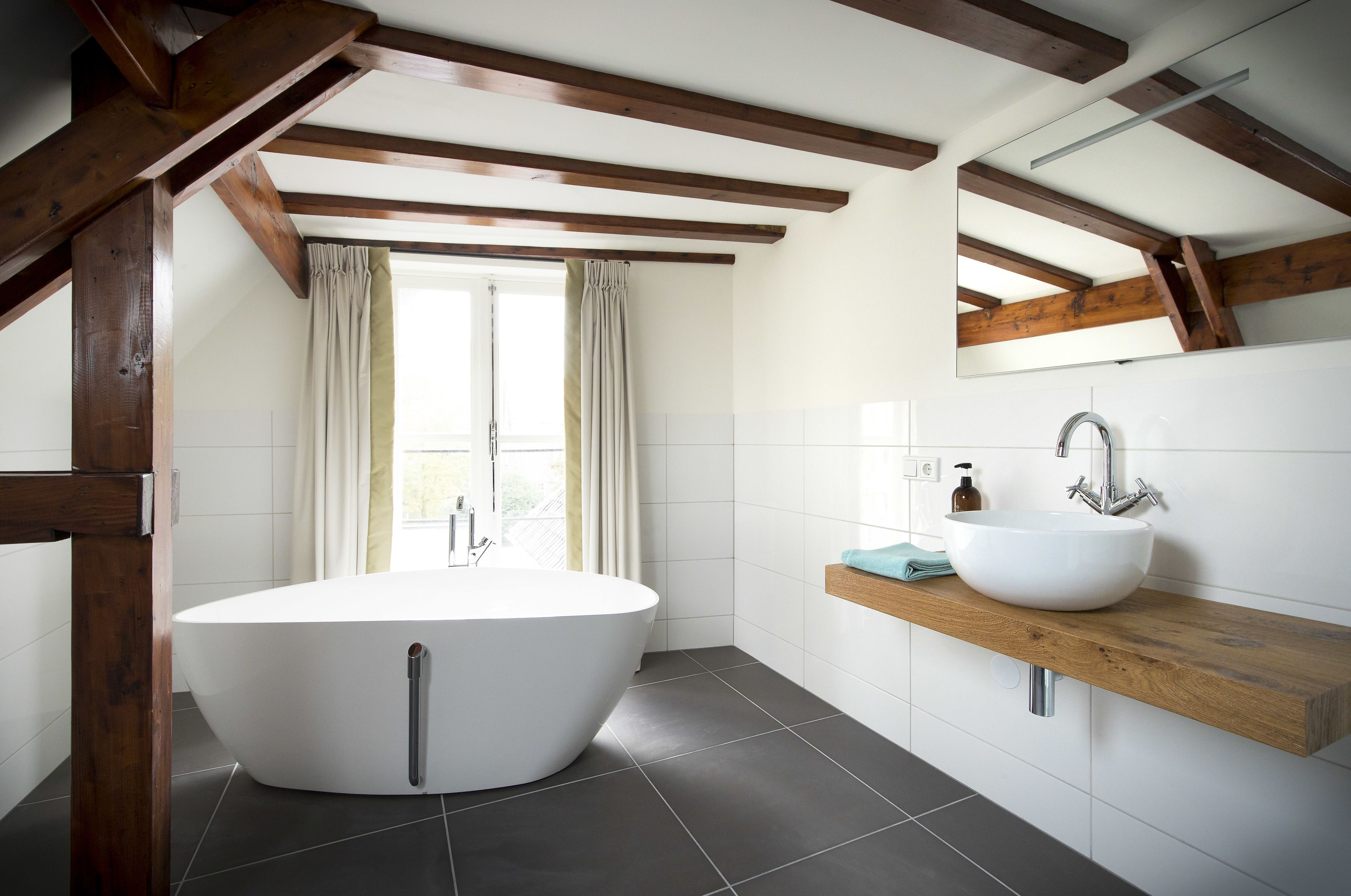 Ein modernes Badezimmer mit einer freistehenden Badewanne, einem Holzkosmetikschrank und einem großen Spiegel.