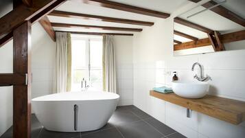 Ein modernes Badezimmer mit einer freistehenden Badewanne, einem Holzkosmetikschrank und einem großen Spiegel.