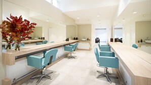 A modern salon with multiple blue chairs, a long counter, and a large mirror.